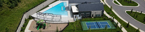 A large building with a pool and tennis court in front.