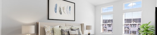 A bedroom with a large bed, a ceiling fan, and a painting on the wall.