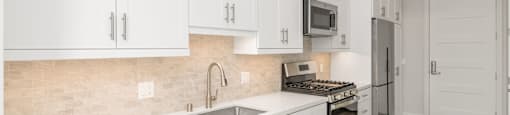 a white kitchen with stainless steel appliances and white cabinets