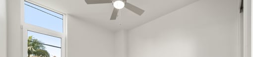 an empty room with white walls and a ceiling fan