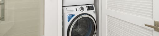 a washing machine in a bathroom with a pattern of arms on the wall