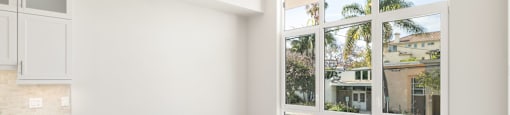 an empty living room with a large window and a kitchen