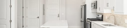 a long hallway with white cabinets and white walls and floors and a white counter top
