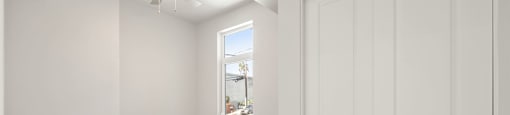 an empty bedroom with white walls and a ceiling fan