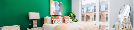a bedroom with a green wall and a bed with orange pillows