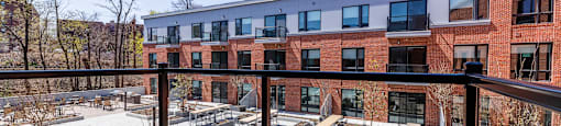 a balcony with a view of a brick building and a deck with benches