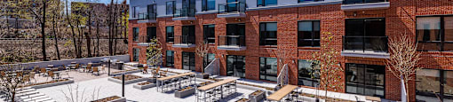 a courtyard with benches and tables in front of a brick building