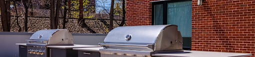 two stainless steel bbqs in front of a brick building