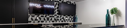 a bar with black stools and a television in a room with a black counter