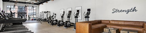 A gym with treadmills, weights, and a bench with the word "Strength" on the wall.