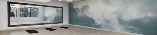 A room with a wooden floor and a wall mural of clouds.