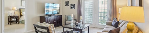 A living room with a television, a chair, a sofa, and a coffee table.