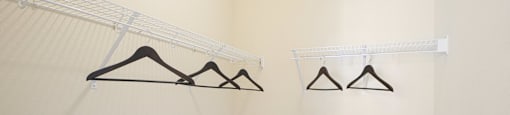 A room with a white wall and a shelf with clothes hanging on it.