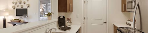 Open concept designer kitchen with upgraded quartz countertops, stainless steel appliances and wood plank floors; kitchen pantry available in select homes; open to living room