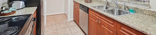 A kitchen with a black stove top oven and wooden cabinets.