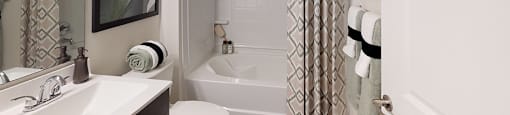 Bathroom with dark cabinets, sink and garden-style bathtub