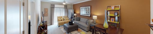 Living room with couch and chair; door to patio or balcony; dining table with two chairs