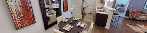 Apartments in Richmond, VA, With In-Unit Washer and Dryer - Clairmont at Chesterfield - Dining Area With Round Table, Chairs, Large Mirror, and Wall Art Next to Open Kitchen.