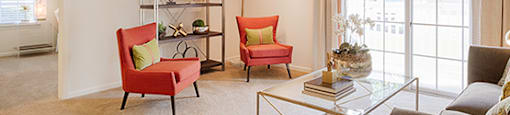 Living room with couch and chair; door to patio or balcony; door to bedroom