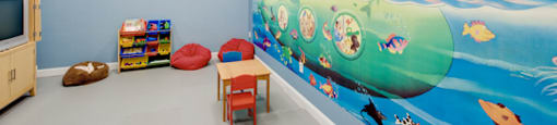 Playroom in fitness center with table and chairs; television; toys