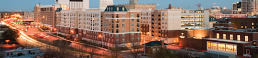 Belmont at Freemason apartment exterior at night; lights of the city and cars driving by