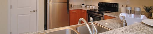 Kitchen with stainless steel appliances; granite countertops; open to living space