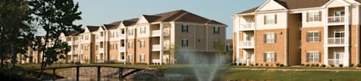 Lake surrounded by apartment buildings; fountain in the center and lakeside walking/jogging trail in the distance