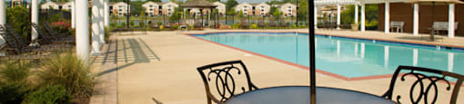 Table and chairs covered by umbrella; swimming pool; pergolas