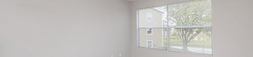 an empty living room with a large window and a ceiling fan
