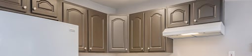 an empty kitchen with white appliances and brown cabinets