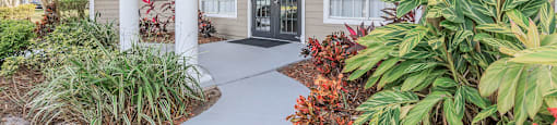 the front entrance of a house with a porch and plants