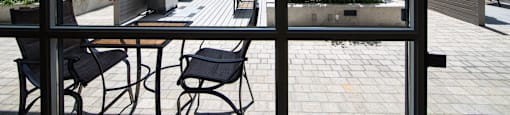 A patio with a table and chairs is seen through a window.