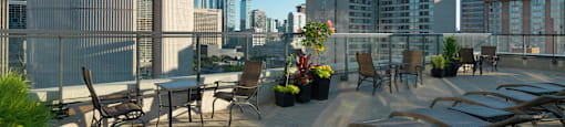 A rooftop patio with chairs and a table with a view of a city skyline.