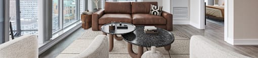 A living room with a brown couch and white chairs.