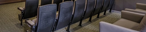 A row of black chairs are lined up in front of a screen in a room.