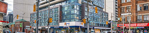 A modern glass building stands tall in a city intersection.