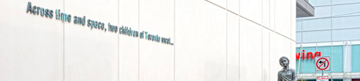 A wall with a plaque that says "Across time and space, two children of Toronto meet."