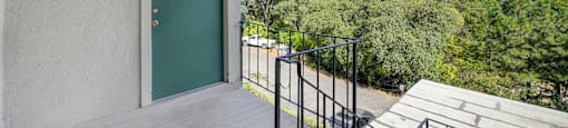 A balcony with a green door and a metal railing.
