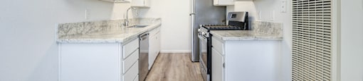 A kitchen with white cabinets and a wooden floor.