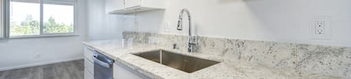 A kitchen with a marble countertop and white cabinets.