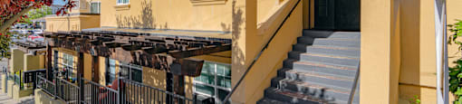 A building with a staircase leading to a black door.