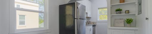 A kitchen with a black refrigerator and wooden floors.
