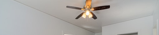 A room with a ceiling fan and wooden floors.