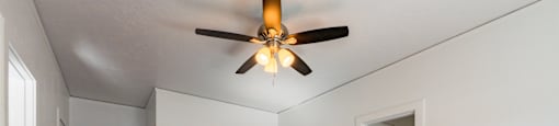 A room with a ceiling fan and wooden floors.