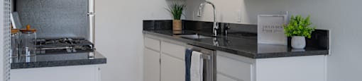A kitchen with white cabinets and a black countertop.