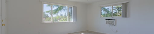 A room with a ceiling fan and two windows.