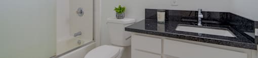 A bathroom with a white toilet, a sink, and a mirror.