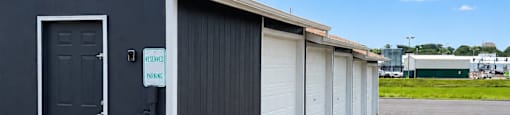 A row of garage doors are closed and the first one is open.