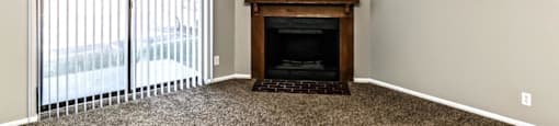 an empty living room with a fireplace and a sliding glass door