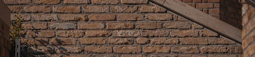 A wall made of bricks with a shadow of a ladder.